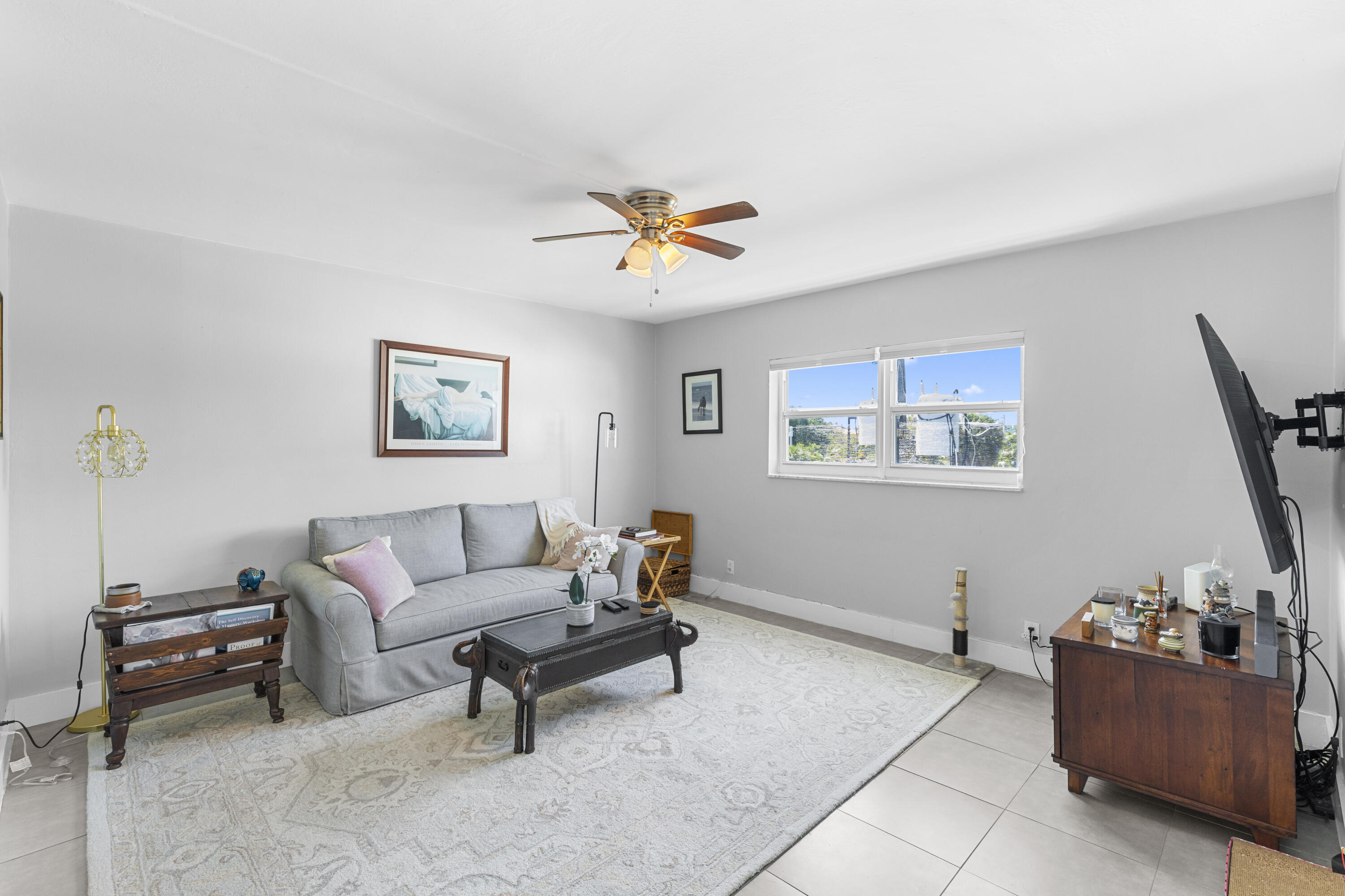 Living room with a gray sofa, patterned rug, wooden furniture, and daylight through the window.