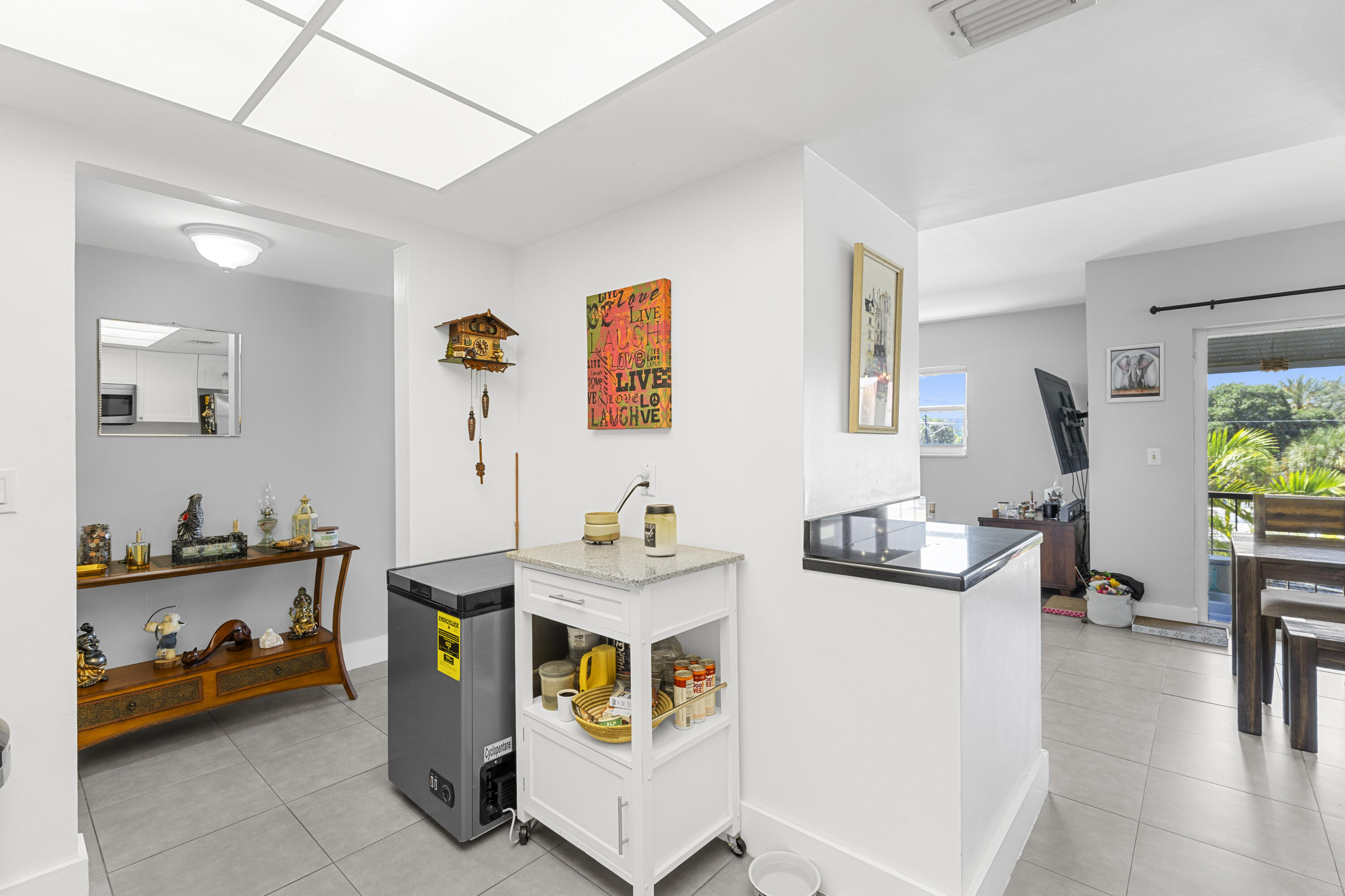 Bright kitchen with a rolling pantry island, gray tile floors, and an adjoining balcony dining area.