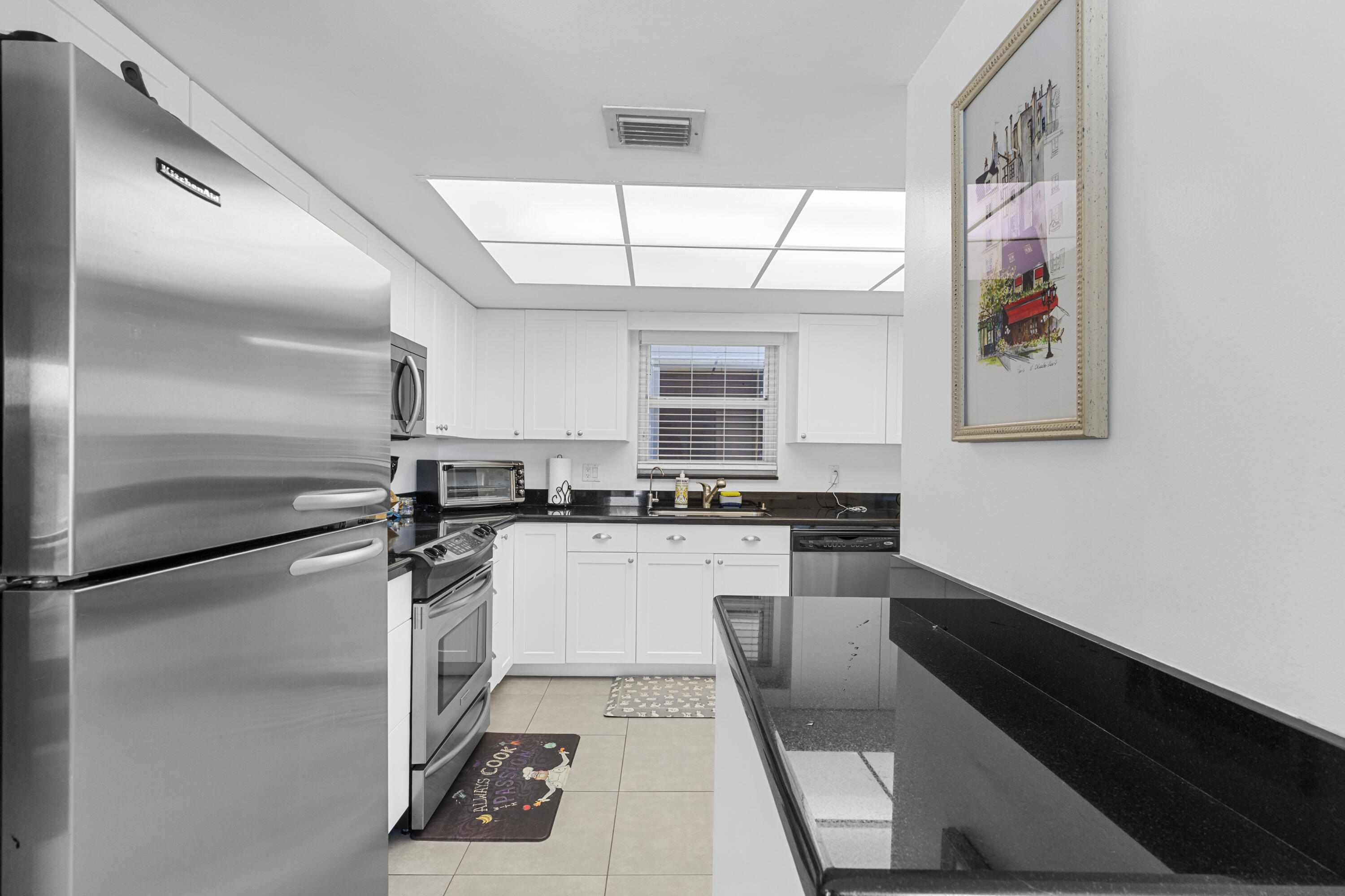 Bright kitchen with white cabinets, black granite counters, and stainless steel appliances.