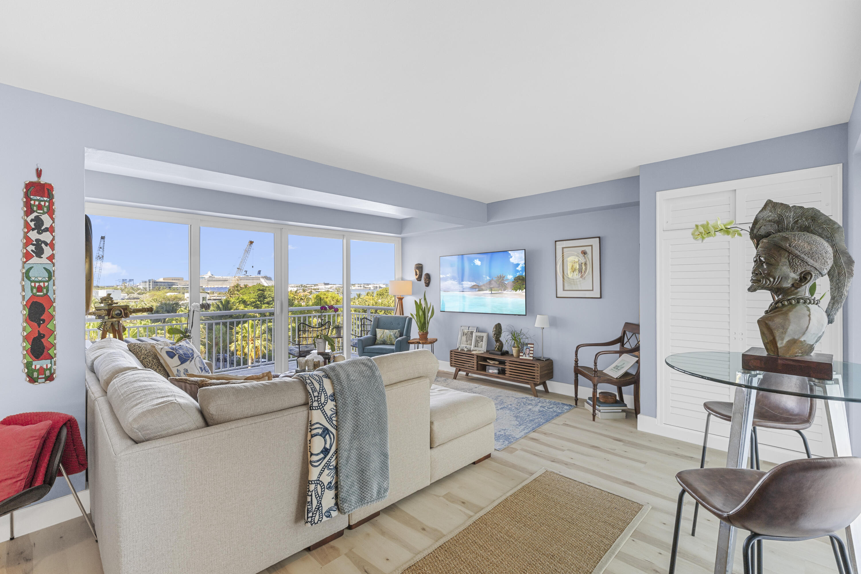 Furnished living room with sliding glass doors opening to a balcony and leafy views.