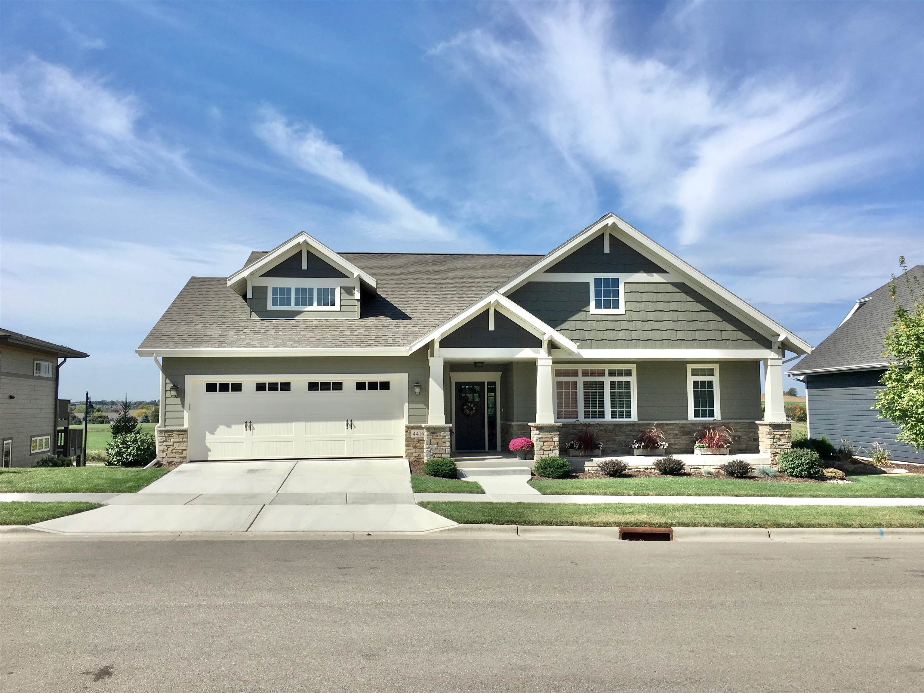 Gray craftsman-style house with white trim, stone accents, and a two-car garage.