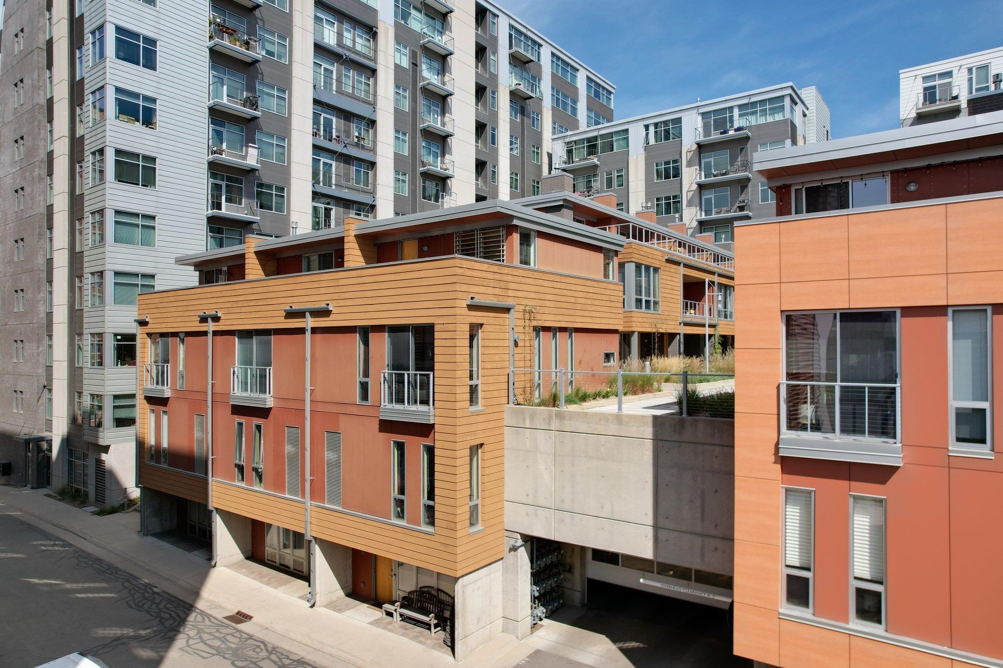 Modern orange-and-wood residential buildings with balconies and taller apartments behind them.