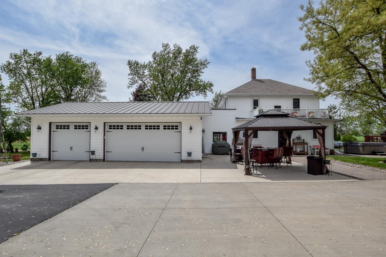 White two-story house with a two-car garage, balcony, and covered patio.