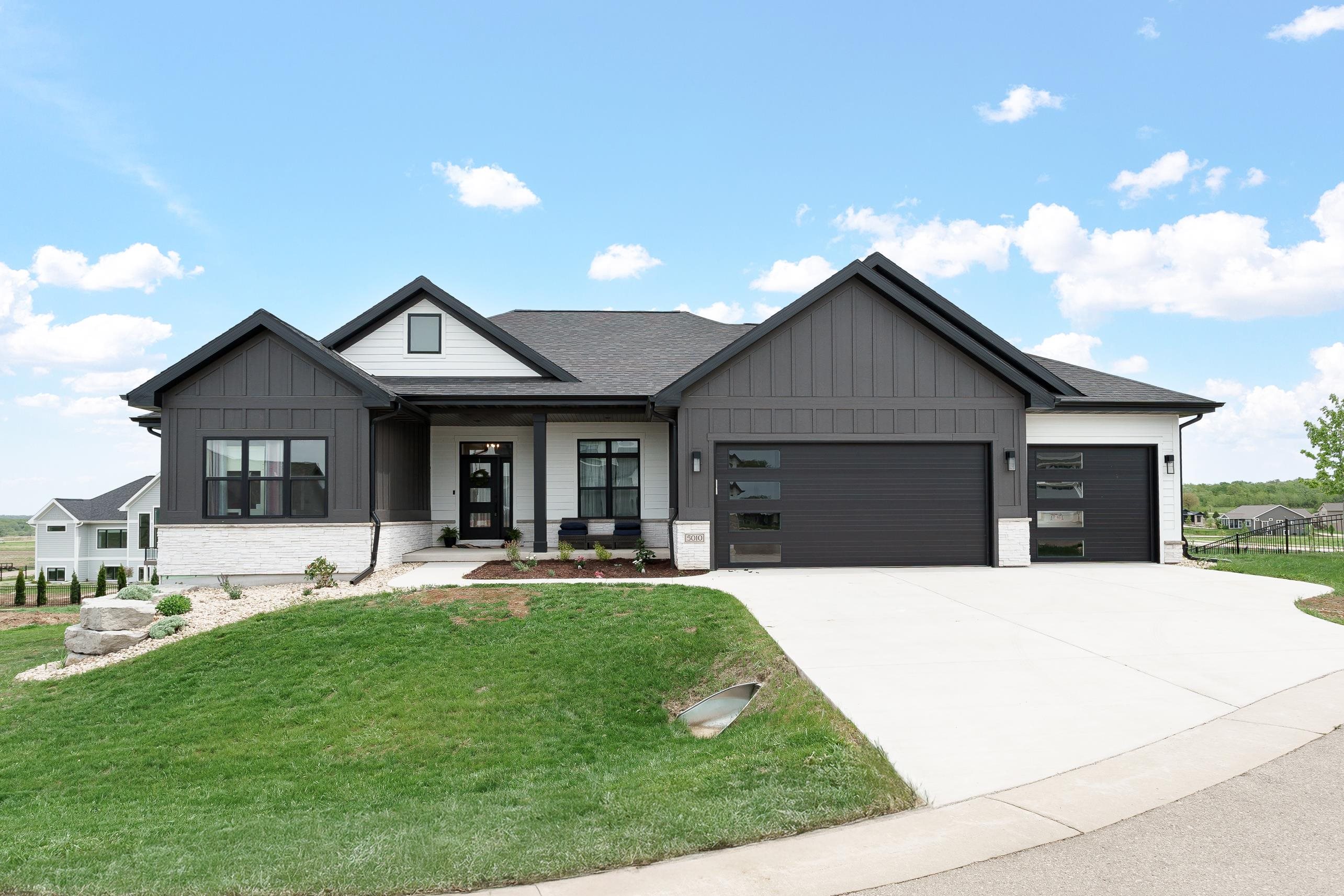 Modern gray-and-white home at 5010 Pear Blossom Court with two dark garage doors.