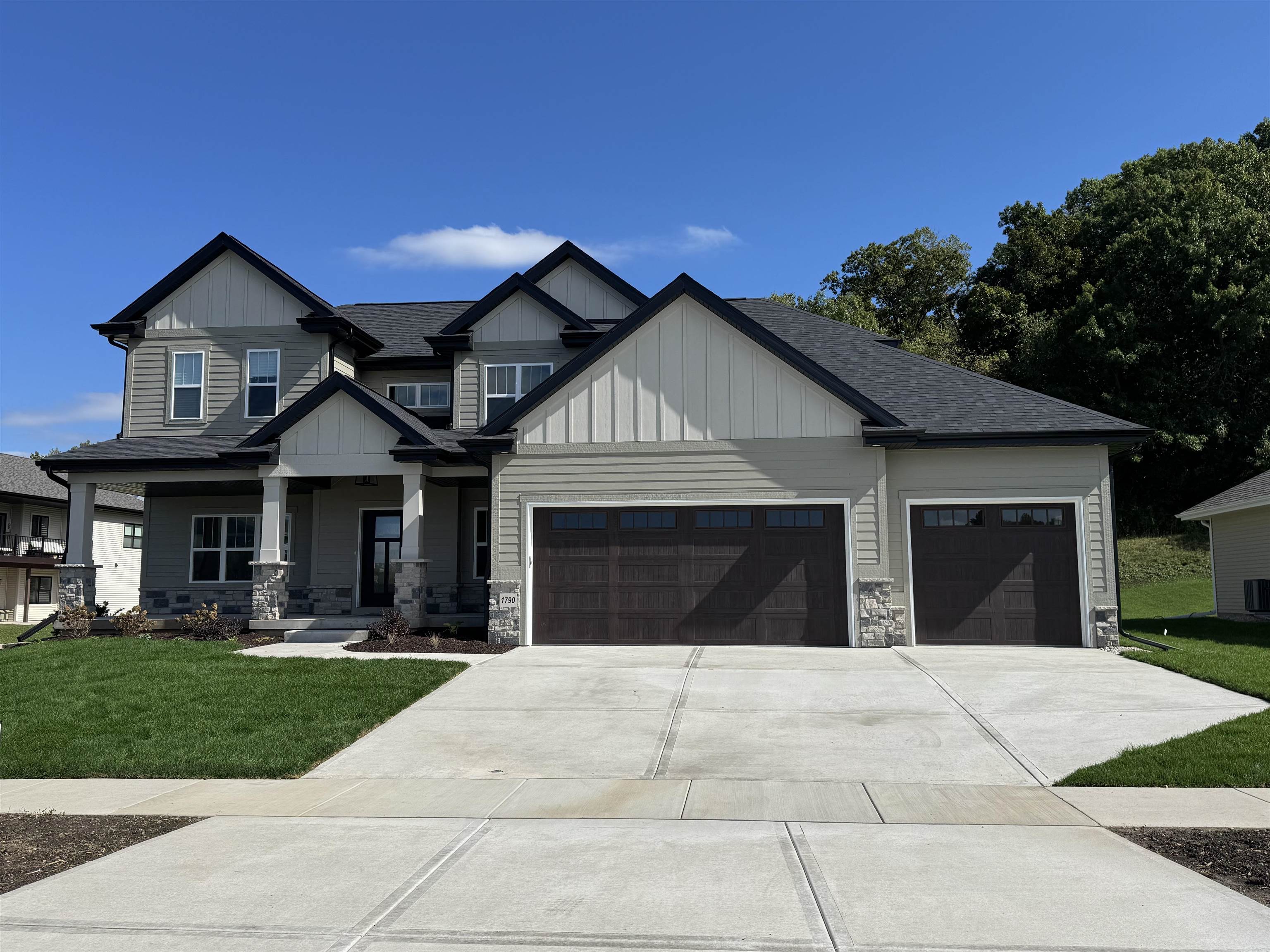 Gray two-story house with white gables, a covered porch, and a three-car garage.