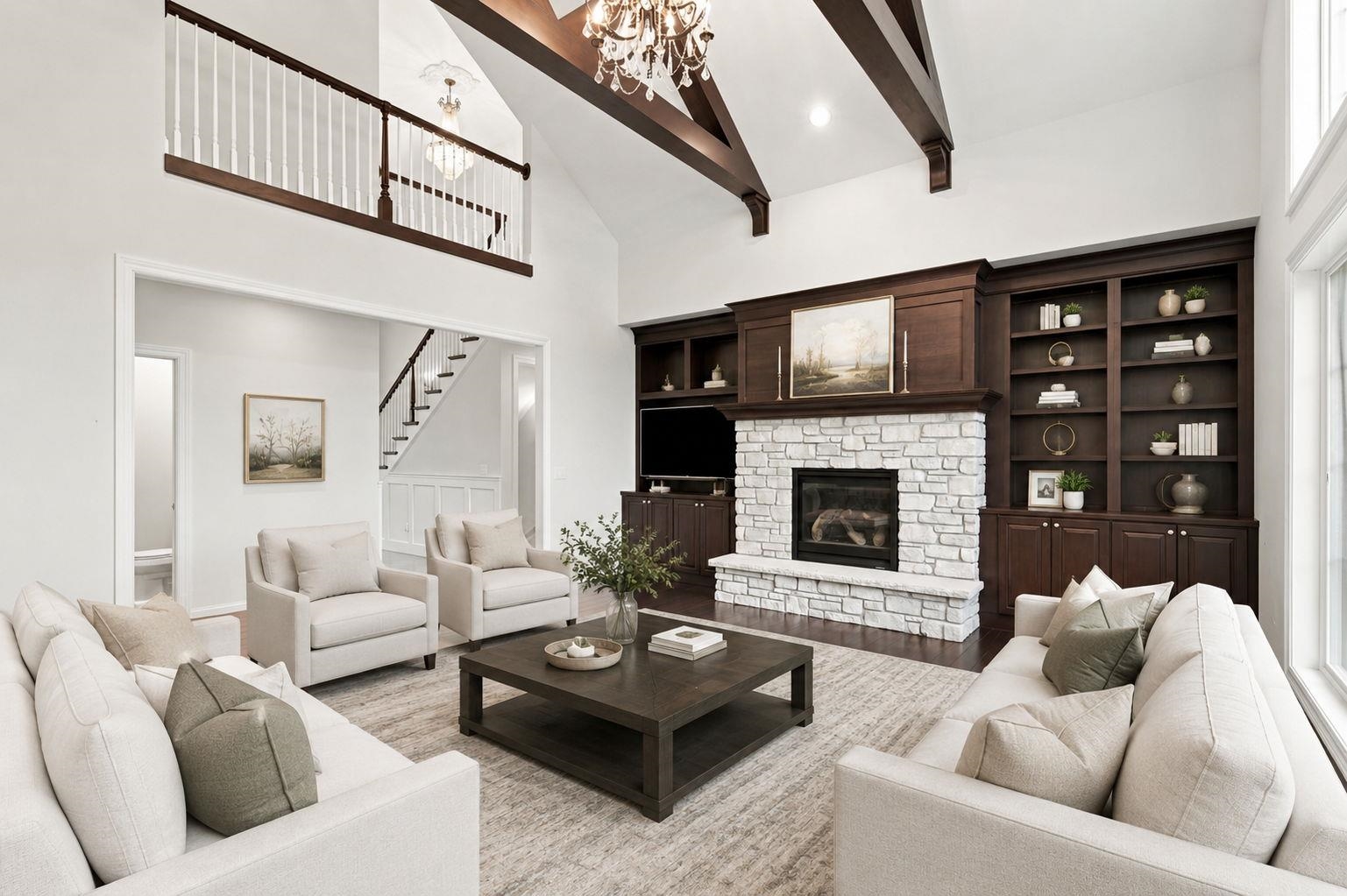 Living room with a white stone fireplace, dark built-ins, exposed beams, and light sofas.