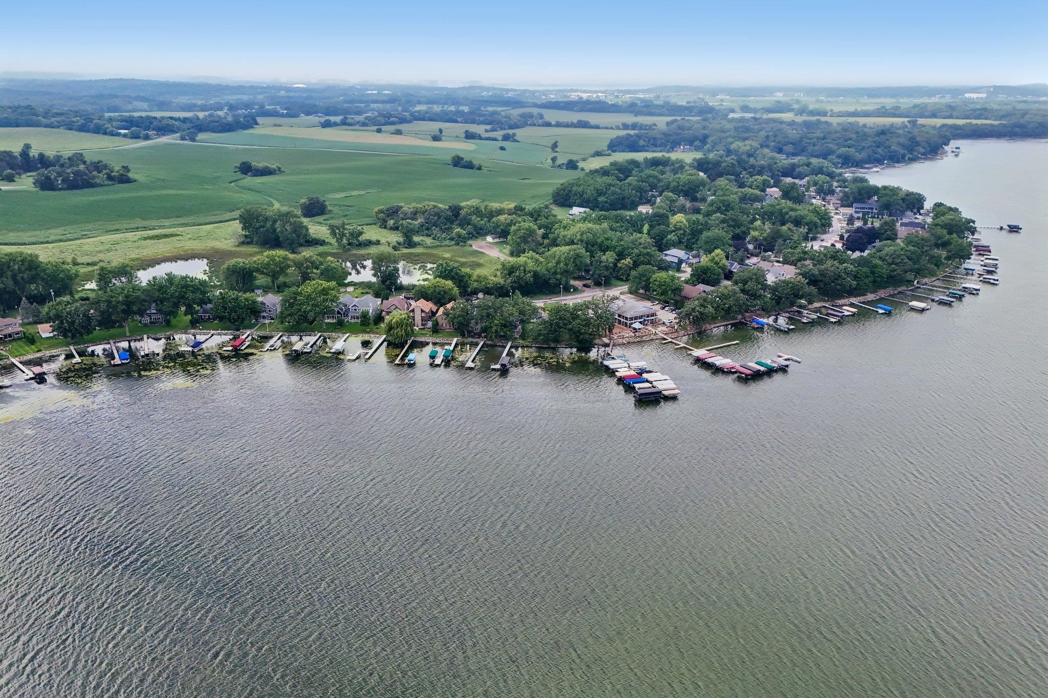 Aerial view of lakeside homes and docks along a tree-lined shore.