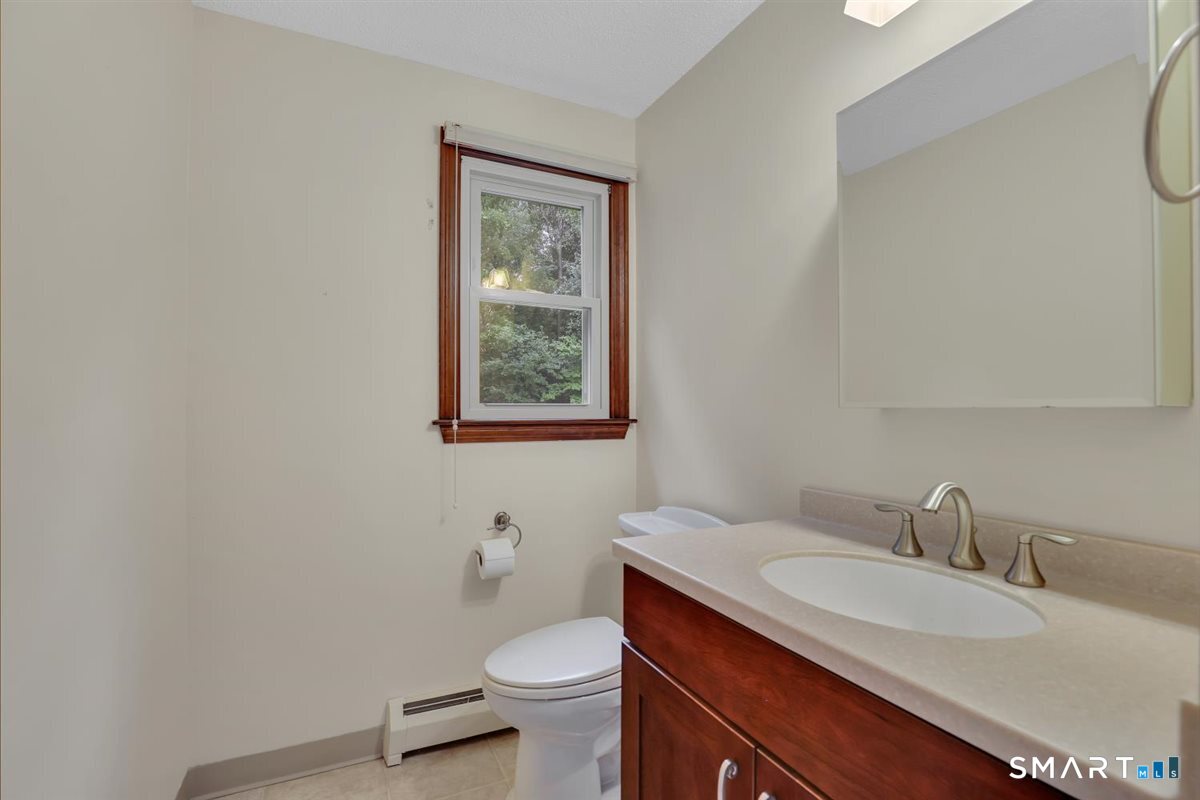 Bathroom with a dark wood vanity, oval sink, and wood-trimmed window.