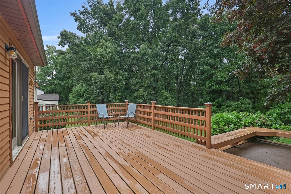 Wooden deck with two chairs and wooded views behind the house.