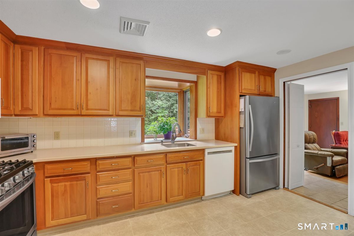 Kitchen with wood cabinets, stainless steel appliances, and a sink beneath a window.