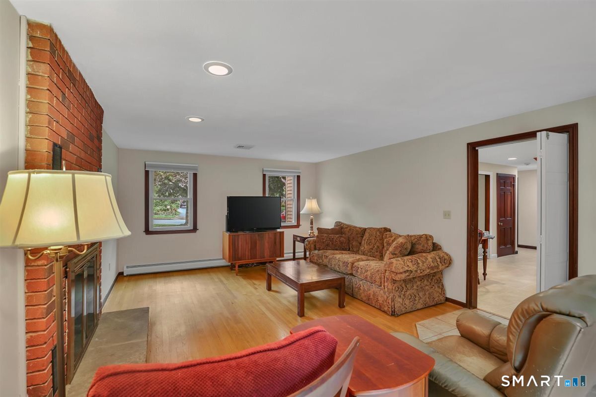 Living room with a brick fireplace, hardwood floors, and a patterned sofa.