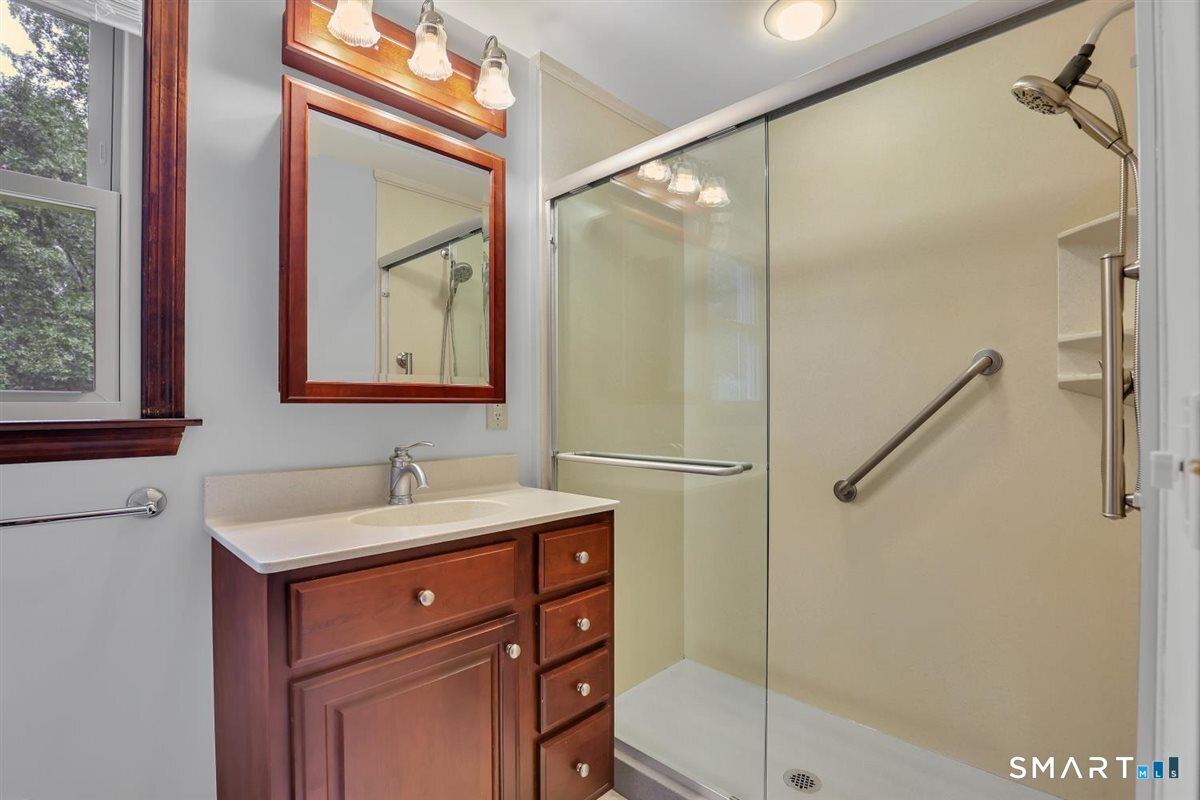 Bathroom with a dark wood vanity and glass shower with grab bars.