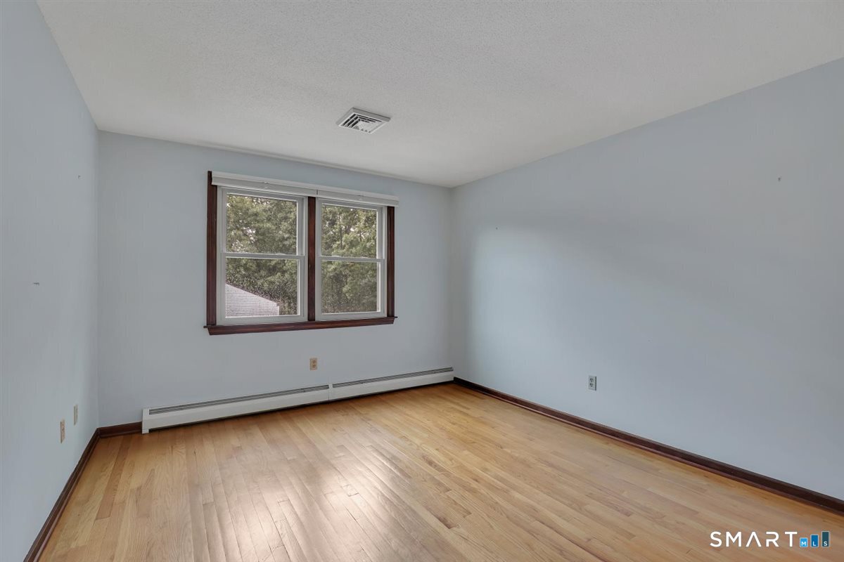 Empty room with hardwood floors, blue walls, dark wood trim, and two windows.