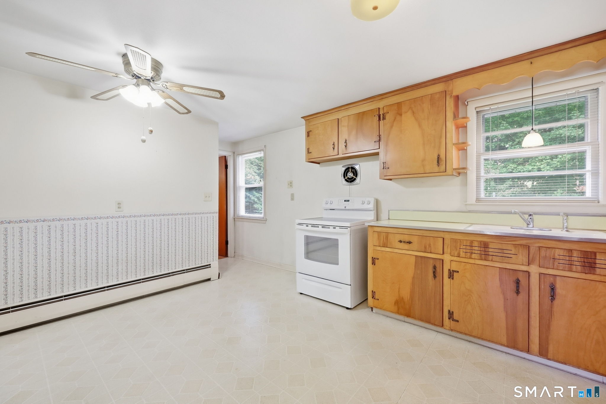 Kitchen with honey-colored cabinets, a white stove, and a window above the sink.
