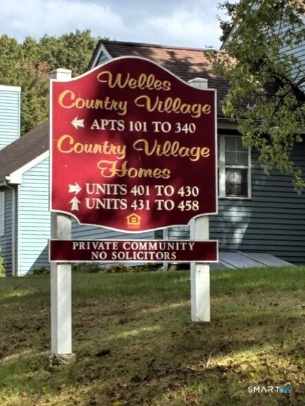 Welles Country Village entrance sign listing apartment and home unit numbers.