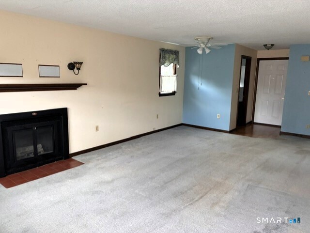 Unfurnished living room with a black fireplace, light carpet, and blue accent wall.