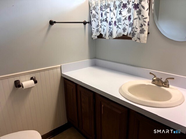 Bathroom vanity with a white countertop, oval sink, dark wood cabinets and floral curtain.