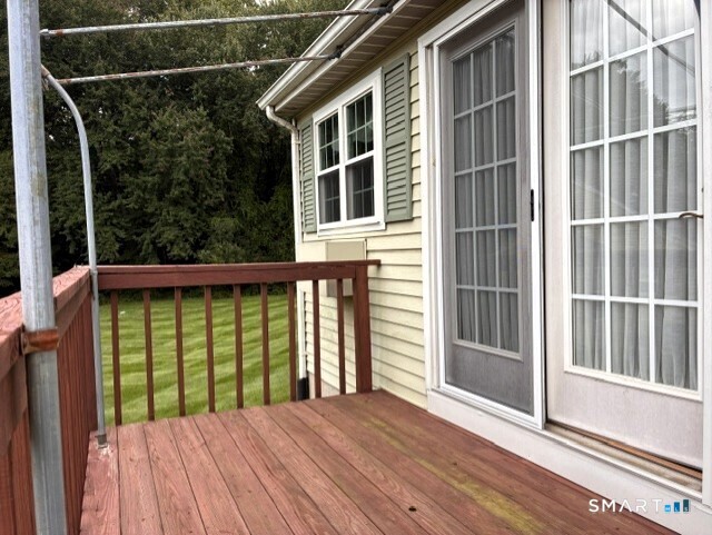 Wooden deck beside sliding glass doors, overlooking a grassy yard and mature trees.