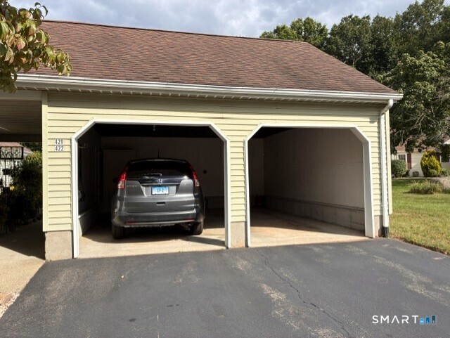 Two-bay detached garage with a gray SUV in one bay and the other bay empty.