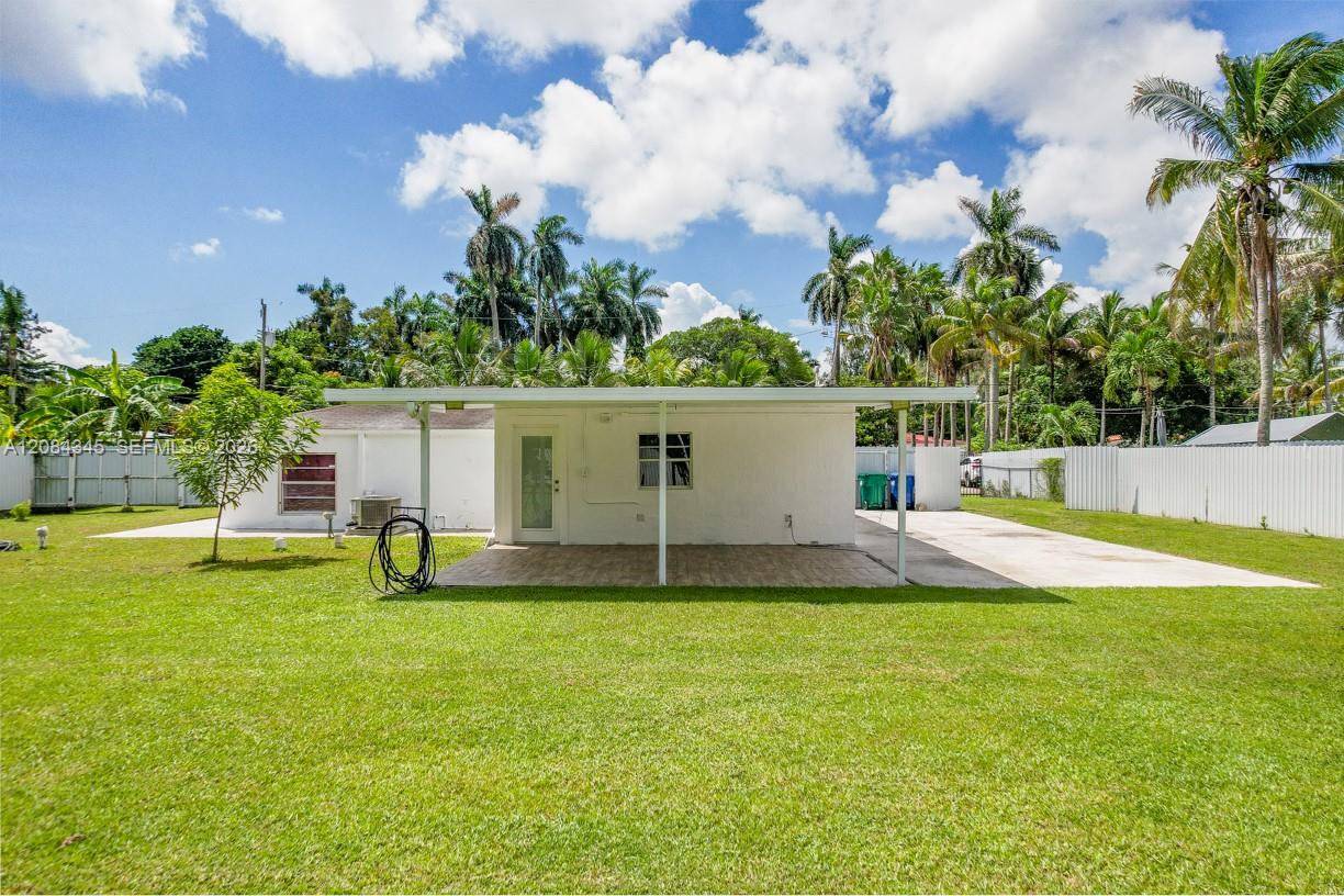 Rear of a white single-story house with a covered patio and spacious lawn.