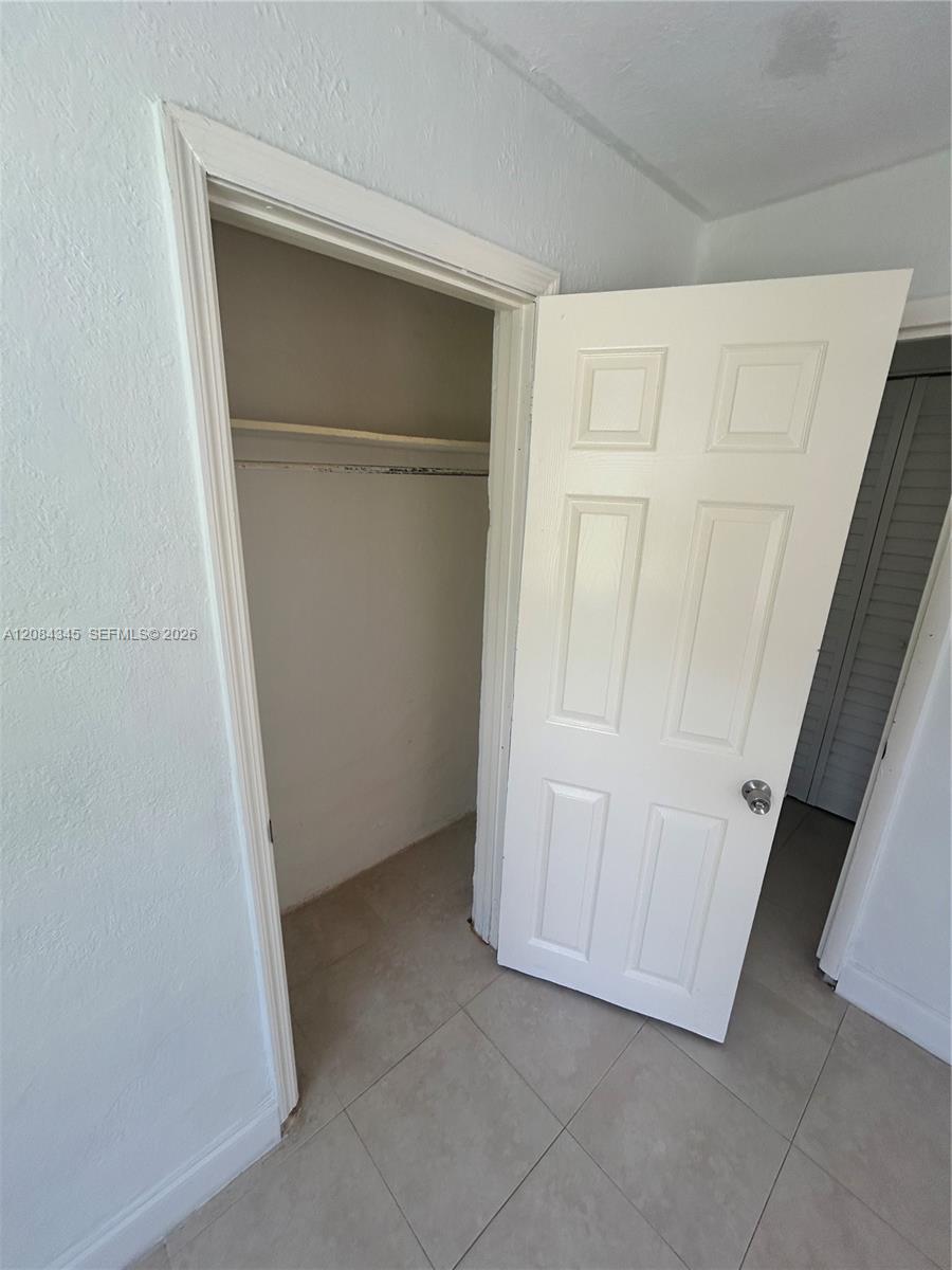 Empty closet with a shelf and hanging rod beside an open white paneled door.