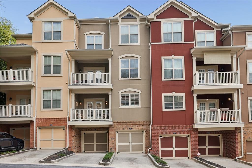 Attached townhomes with tan and red facades, white balconies, and ground-level garages.