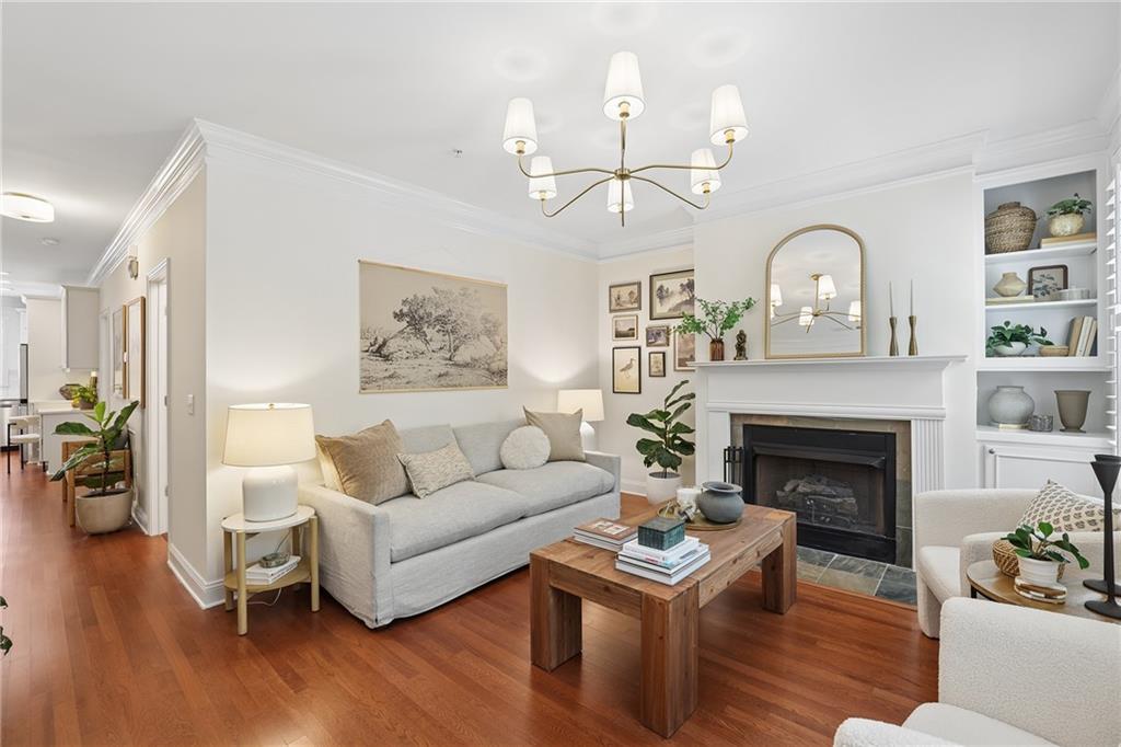 Living room with a white sofa, hardwood floors, and a fireplace beneath a large mirror.