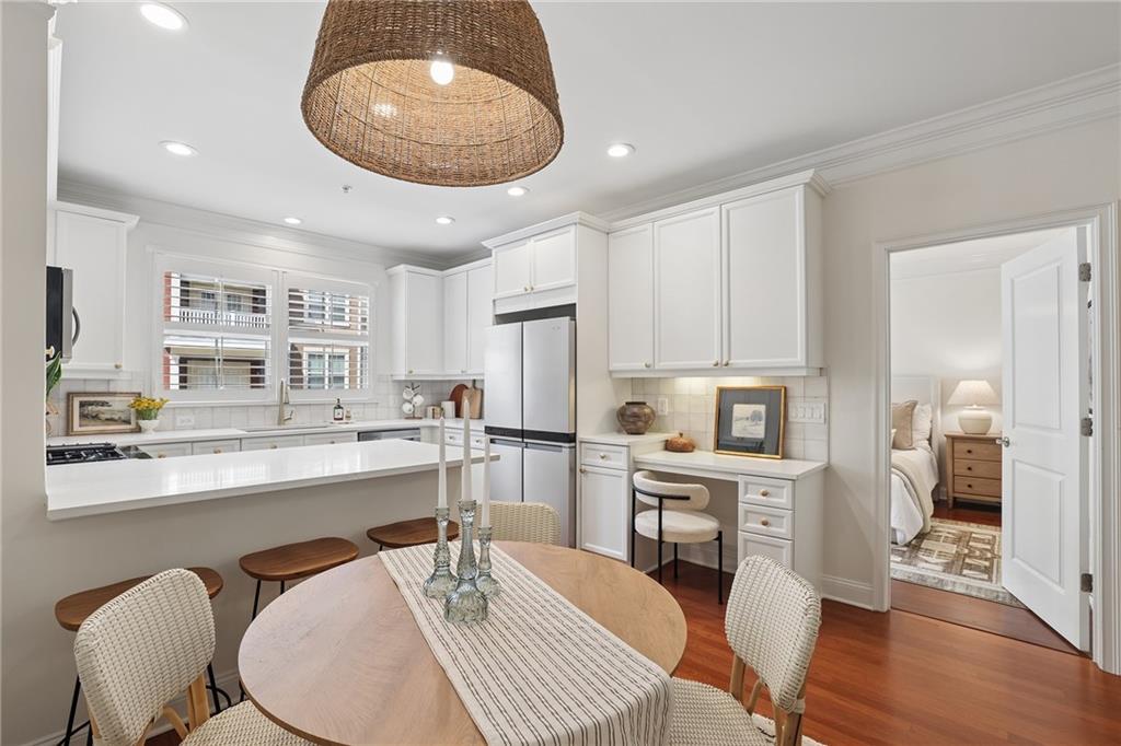 Kitchen and dining area with a broad breakfast bar, round wood table, and doorway to a bedroom.