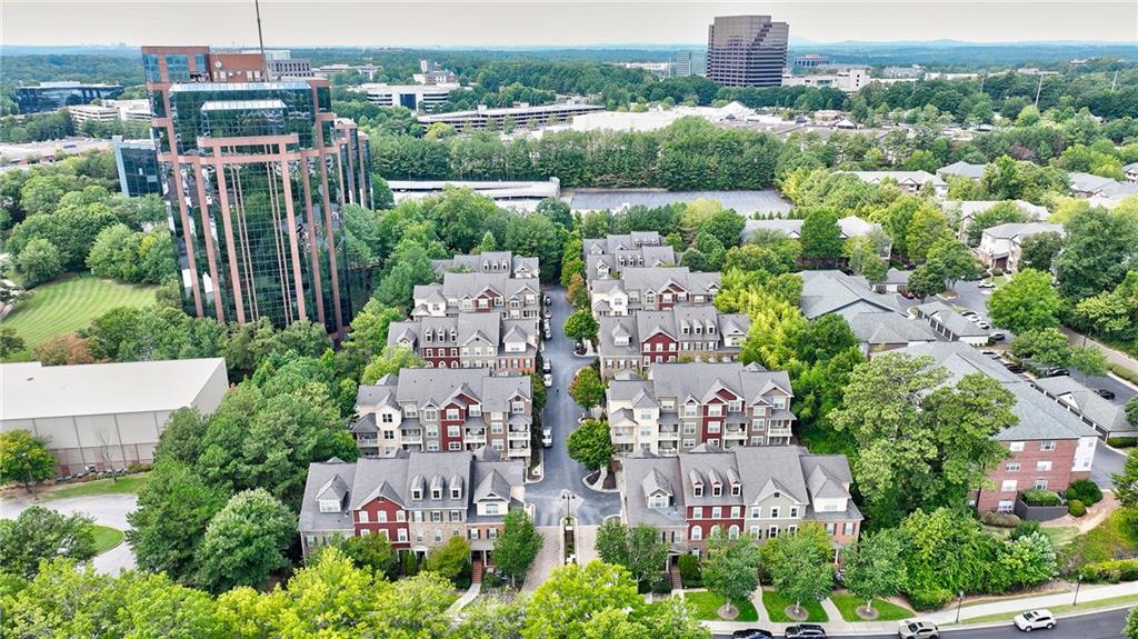Aerial view of a townhome community with tree-lined streets and nearby office towers.