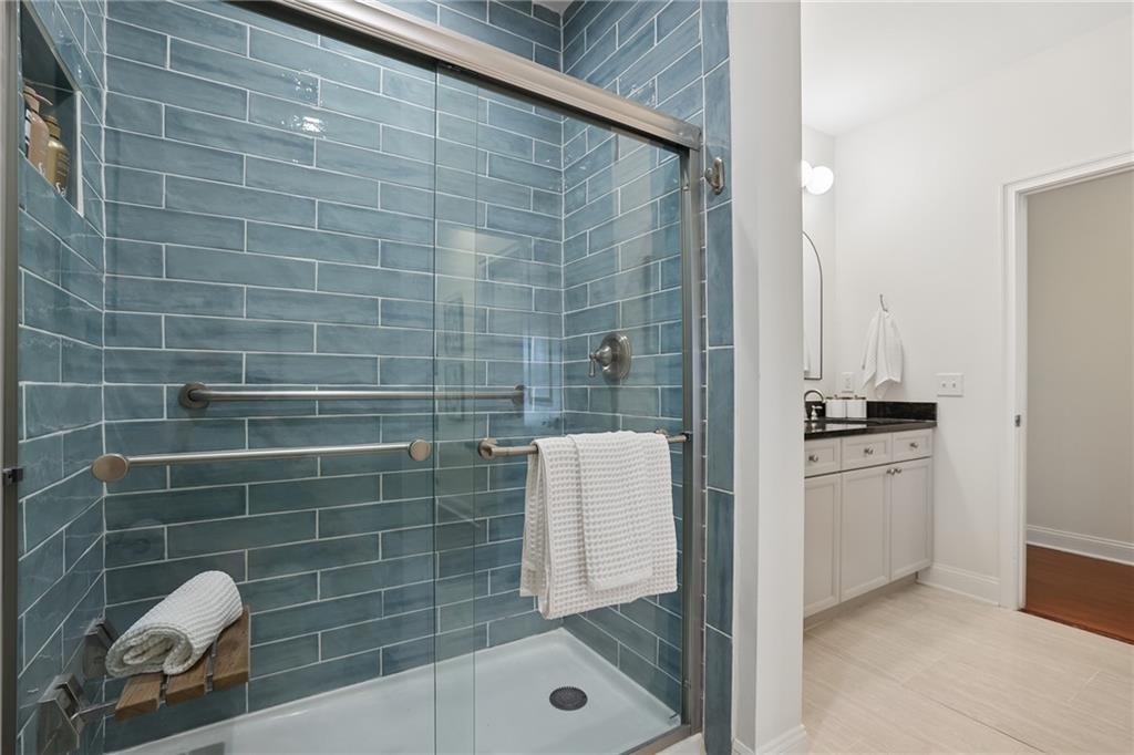 Bathroom with a blue-gray tiled glass shower and white vanity.