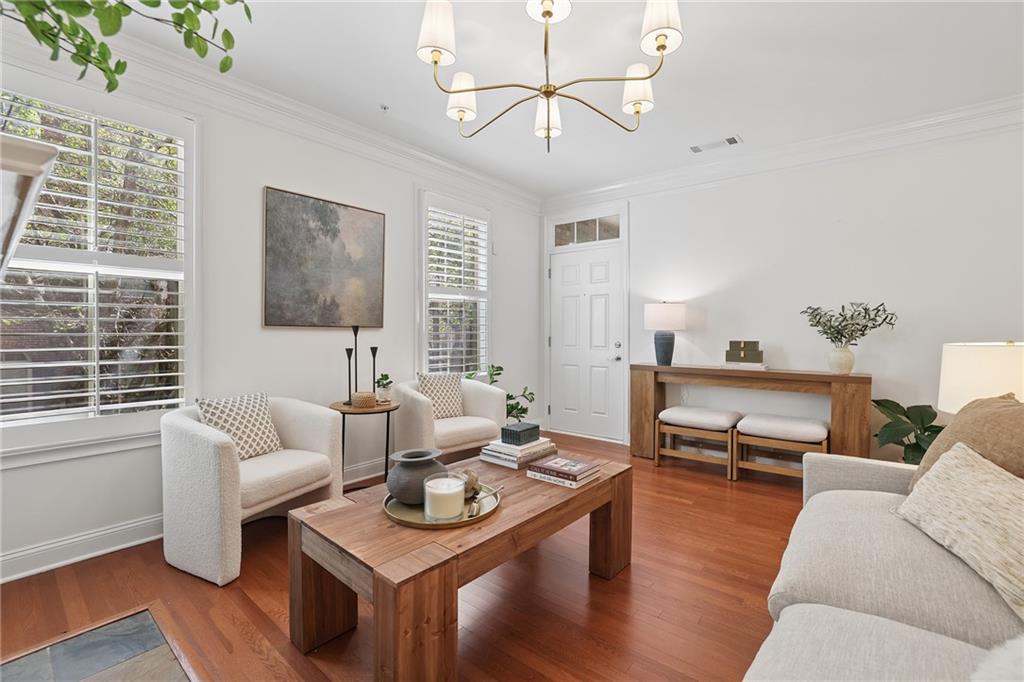 Living room with hardwood floors, shuttered windows, and a wood coffee table.