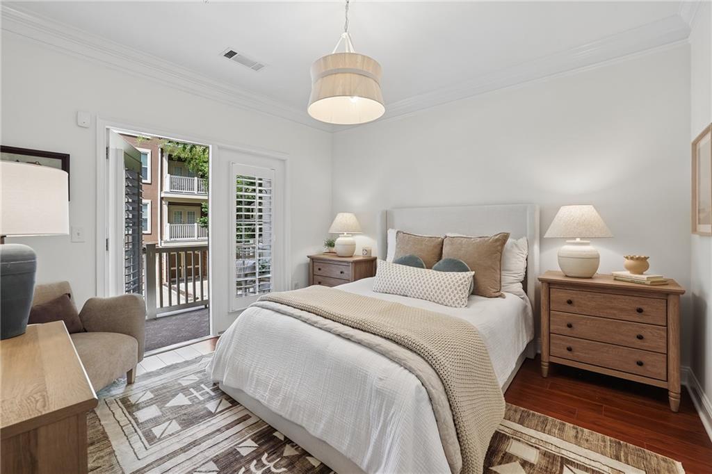 Staged bedroom with a white bed, matching bedside tables, and an open door to a balcony.
