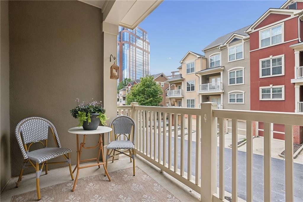 Furnished apartment balcony overlooking neighboring buildings and a glass office tower.