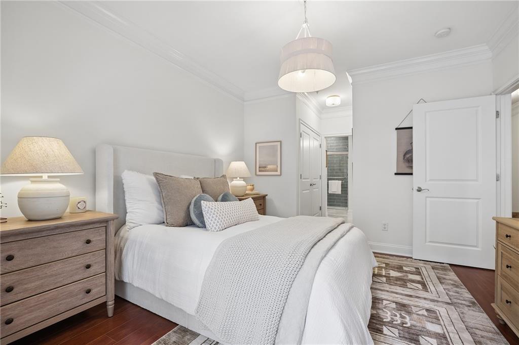 Staged bedroom with a white upholstered bed, neutral bedding, wood dressers, and a geometric rug.