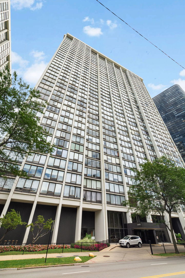 High-rise condominium at 5445 N Sheridan Road, with a landscaped entrance and rows of windows.