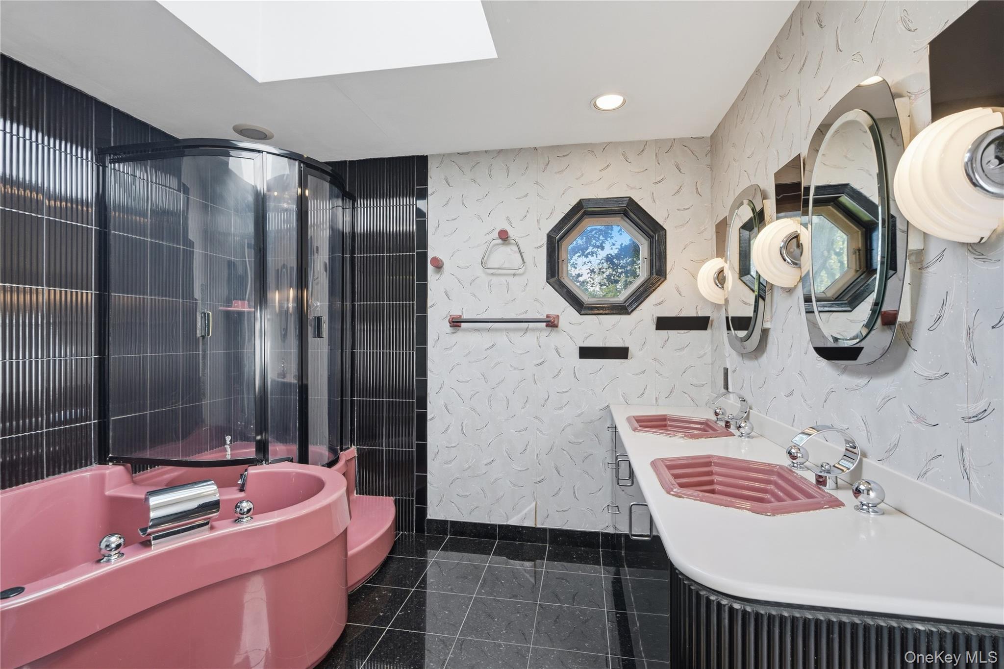 Bathroom with a pink jetted tub, glass shower, and double pink sinks.