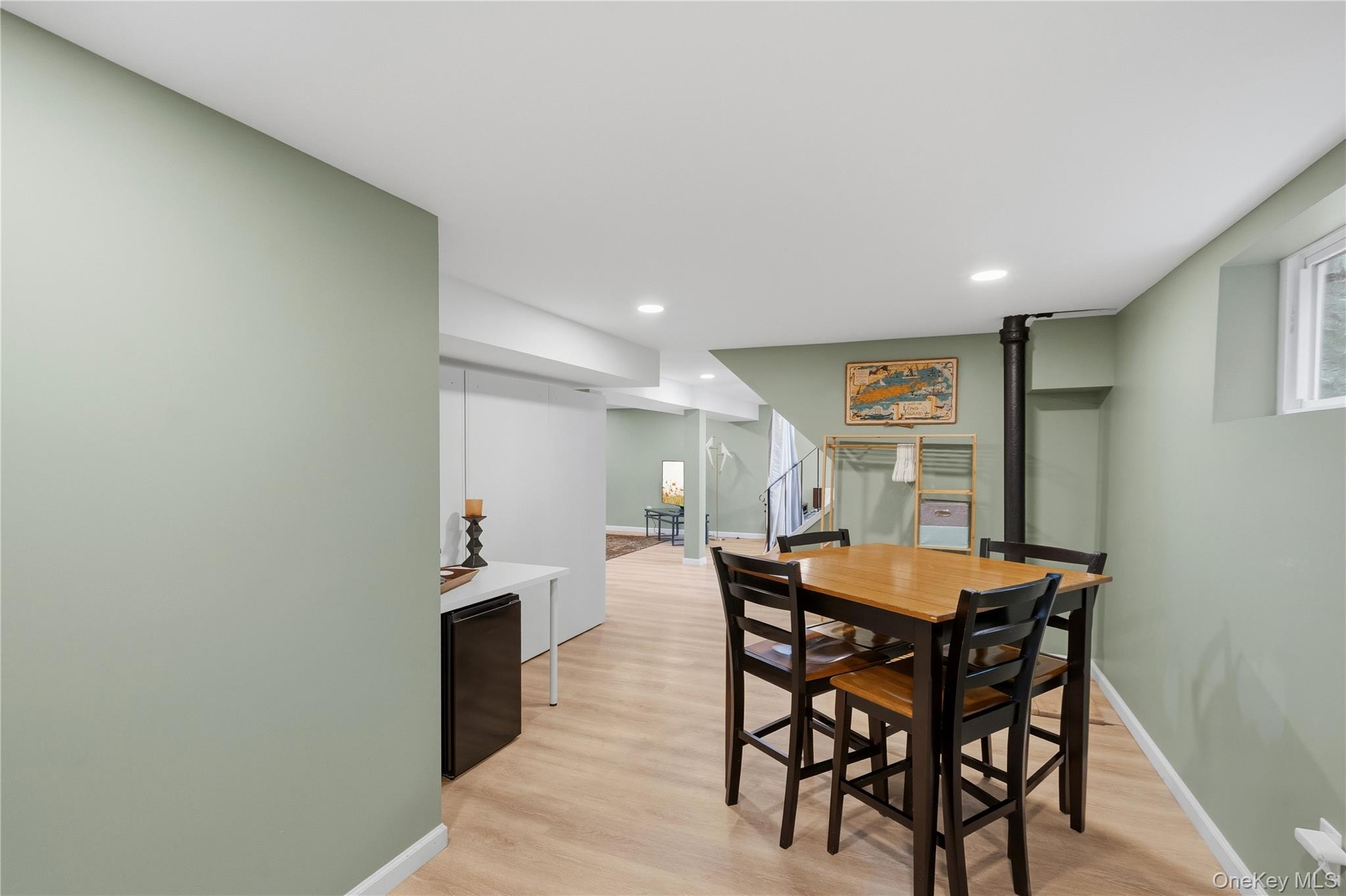 Dining area with a wooden table, dark chairs, pale green walls, and a black stove pipe.