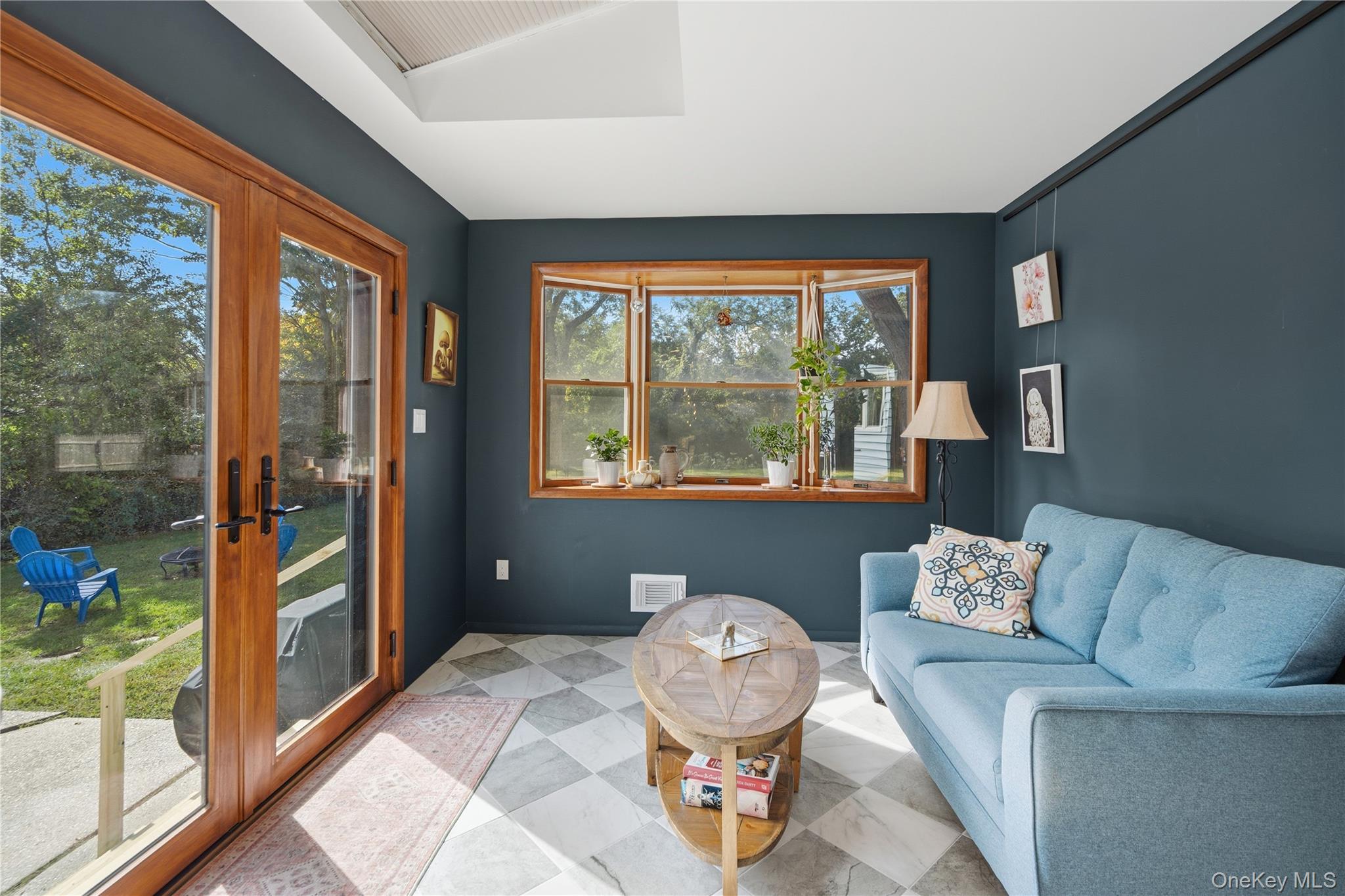 Sunroom with a light blue sofa, wood-framed windows, and glass doors opening to the yard.