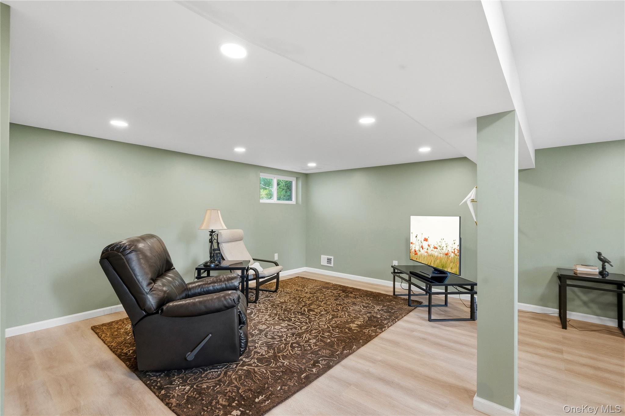 Furnished basement sitting area with a leather recliner, patterned rug, and television.
