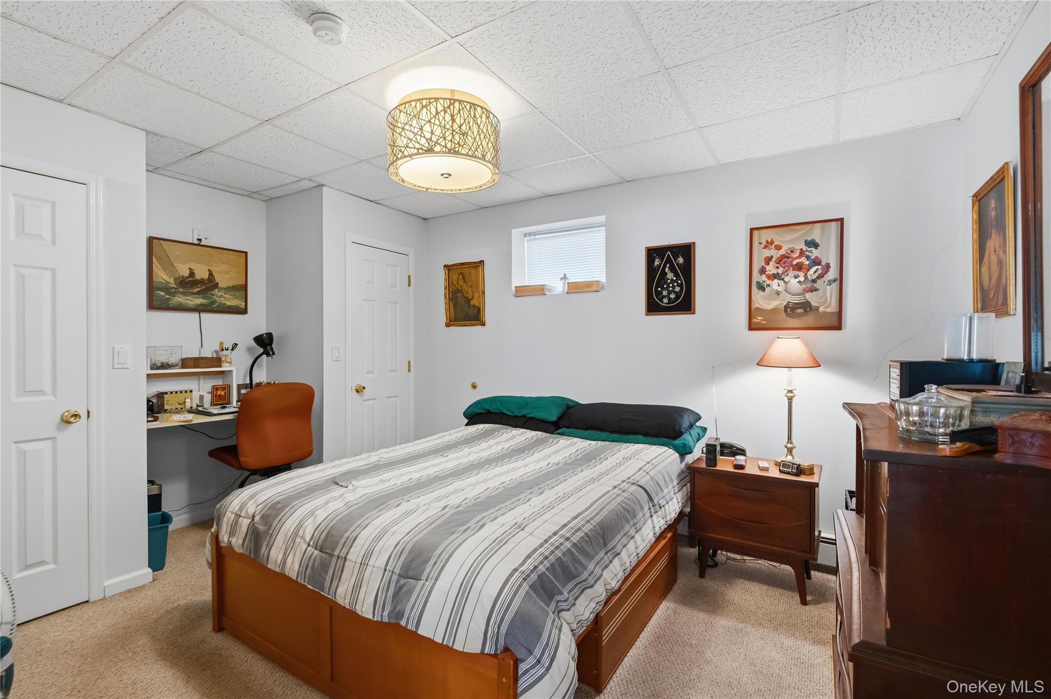 Bedroom with a wooden bed, striped bedding, framed artwork, and a small desk nook.