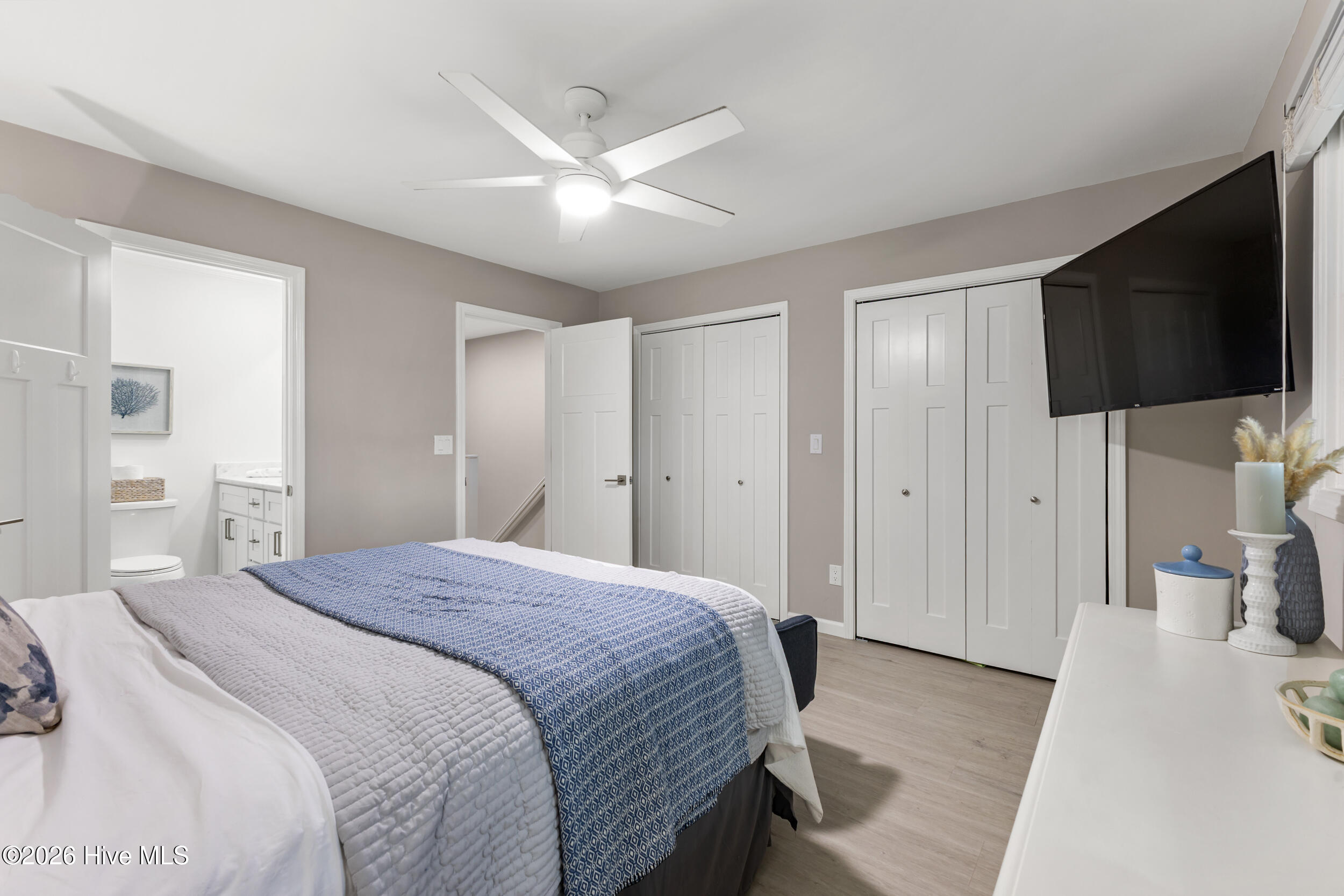 Bedroom with blue patterned bedding, a large wall-mounted television, and an adjoining bathroom.