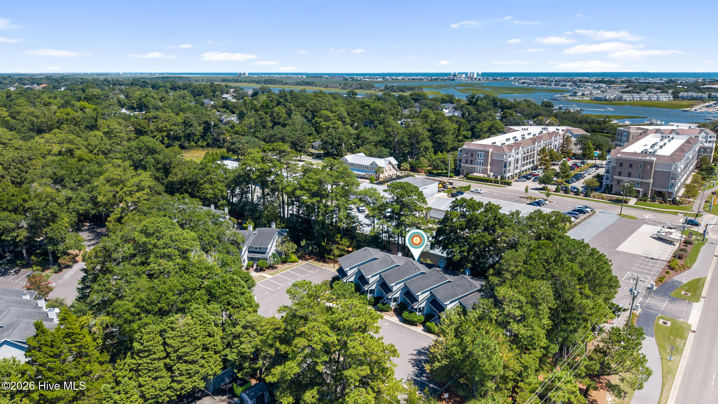 Aerial view of townhomes among trees, with waterways and the ocean in the distance.