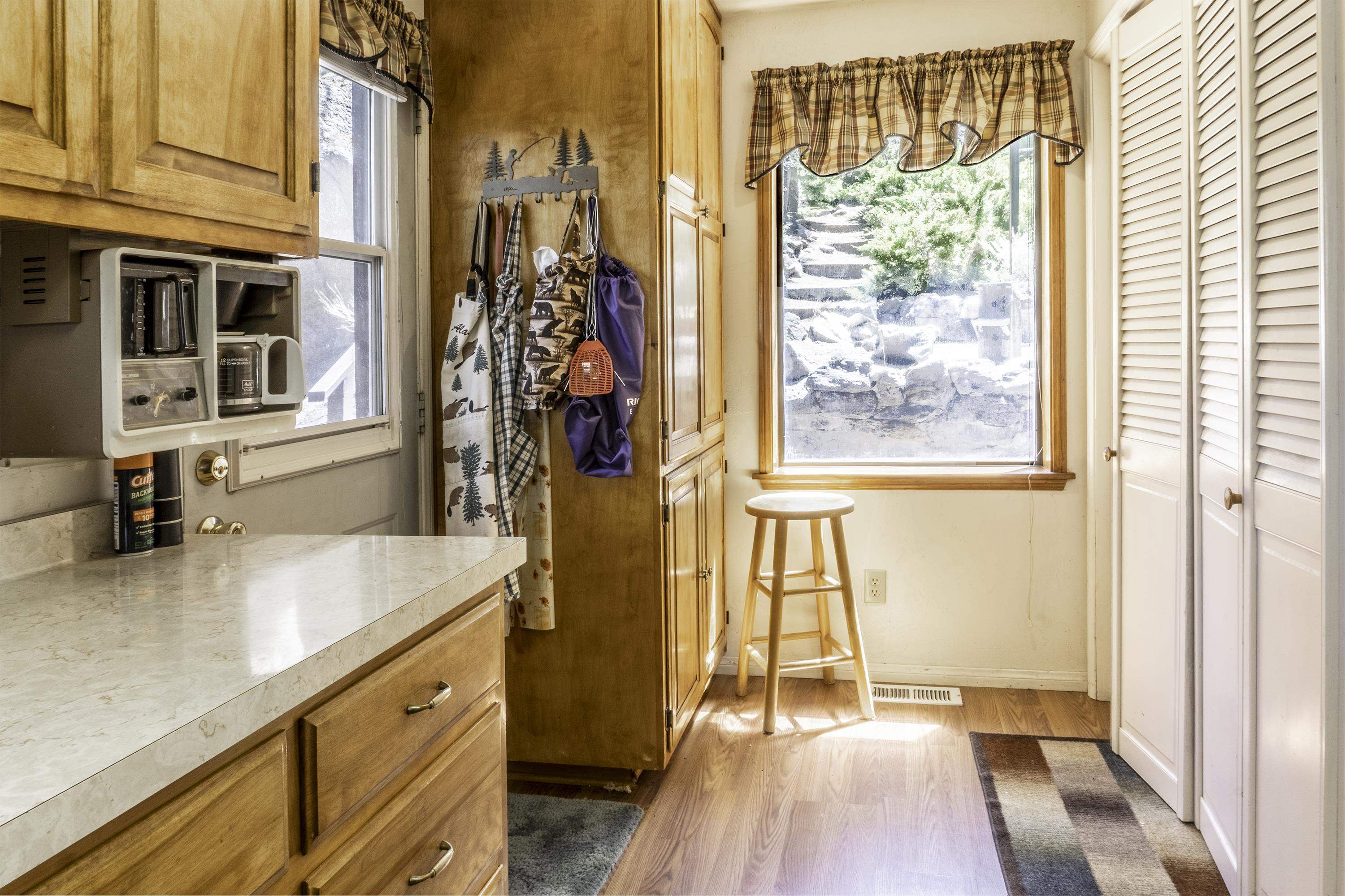 Kitchen with wood cabinetry, a long counter, and a bright window overlooking stone steps.