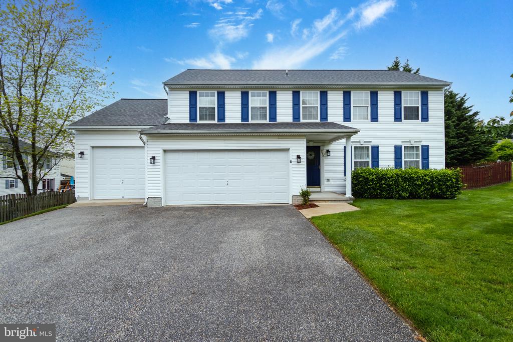 White two-story house with blue shutters, an attached two-car garage, and a wide driveway.