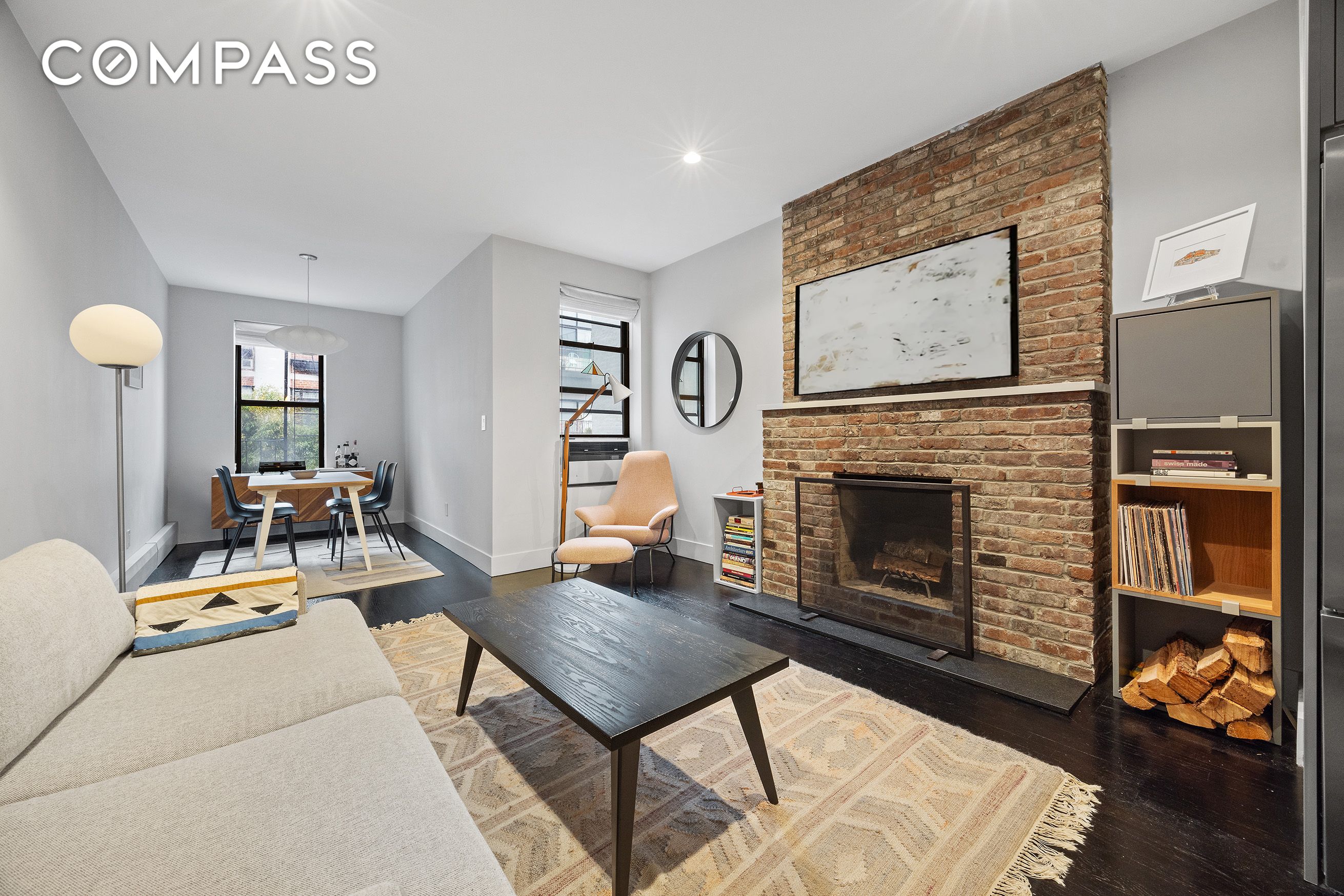 Living room with an exposed-brick fireplace, cream sofa, and adjoining dining area.