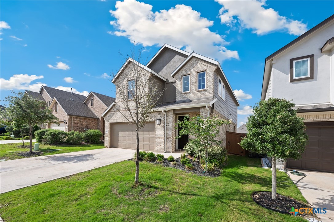 Two-story stone-and-brick home with a double garage, covered entry, and landscaped front lawn.