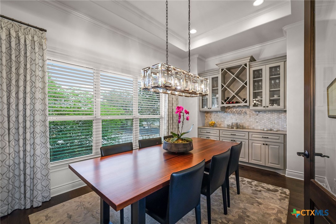 Dining room with a wood table, geometric chandelier, and built-in glass-front cabinets.