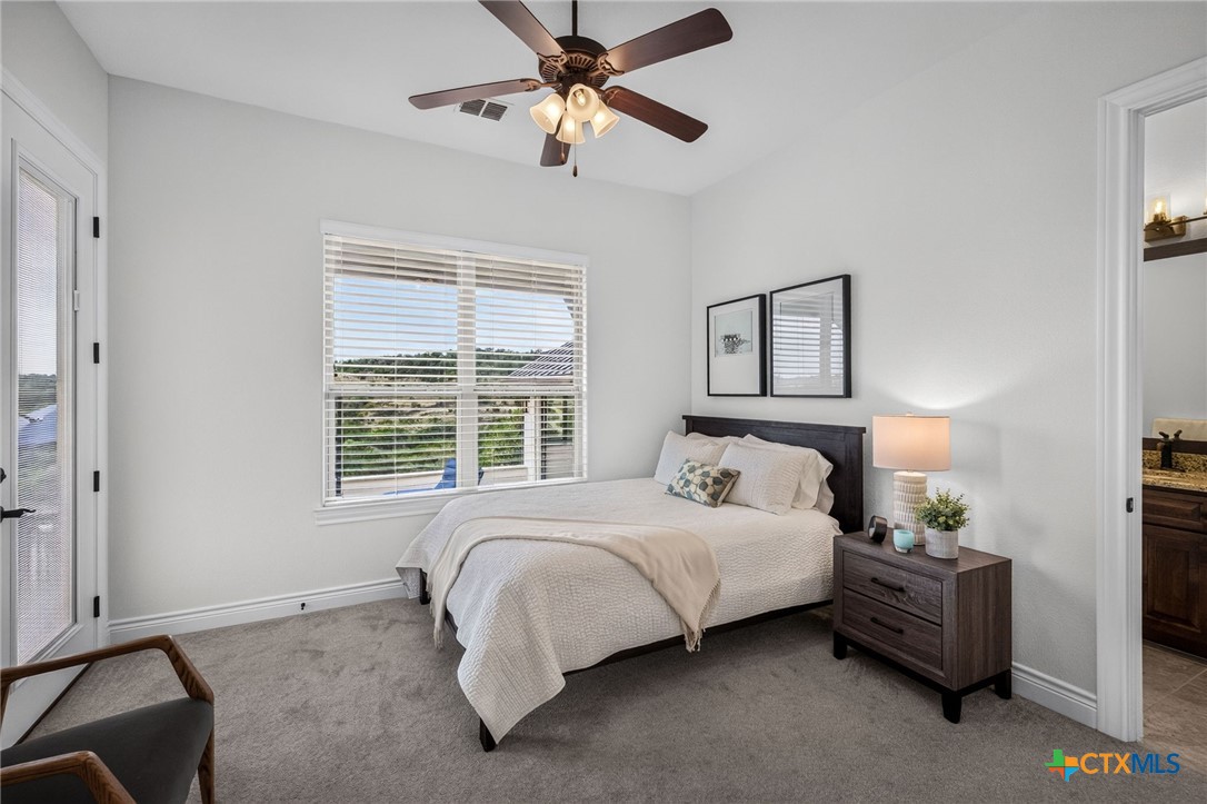 Furnished bedroom with a white bed, dark wood headboard, ceiling fan, and window with blinds.