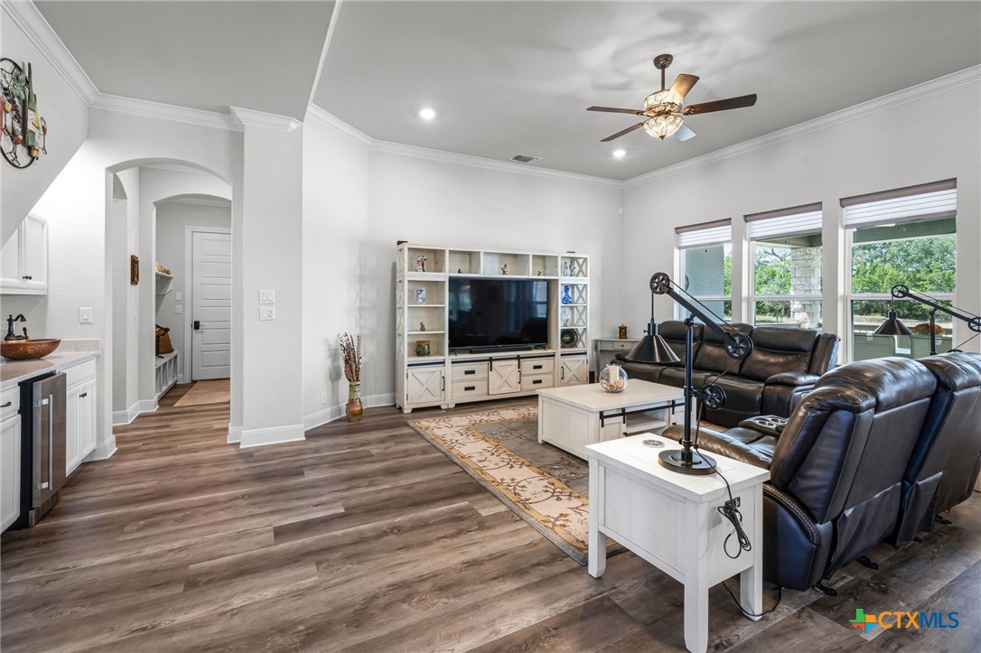 Living room with leather reclining sofas, a white entertainment center, and windows overlooking trees.