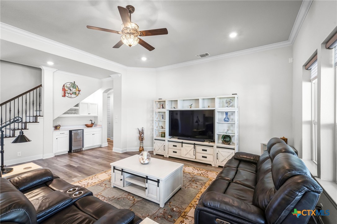 Furnished living room with dark leather sofas, a large television, and a white built-in entertainment unit.